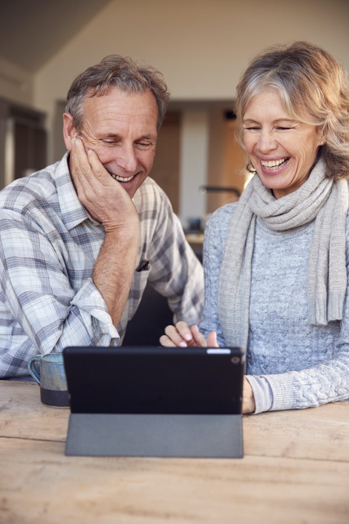 Retired Senior Couple At Home Buying Products Or Services Online Using Digital Tablet